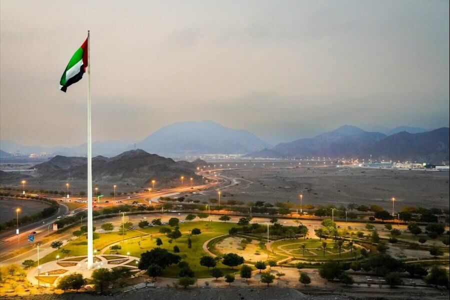 UAE flag flying over a city landscape at dusk